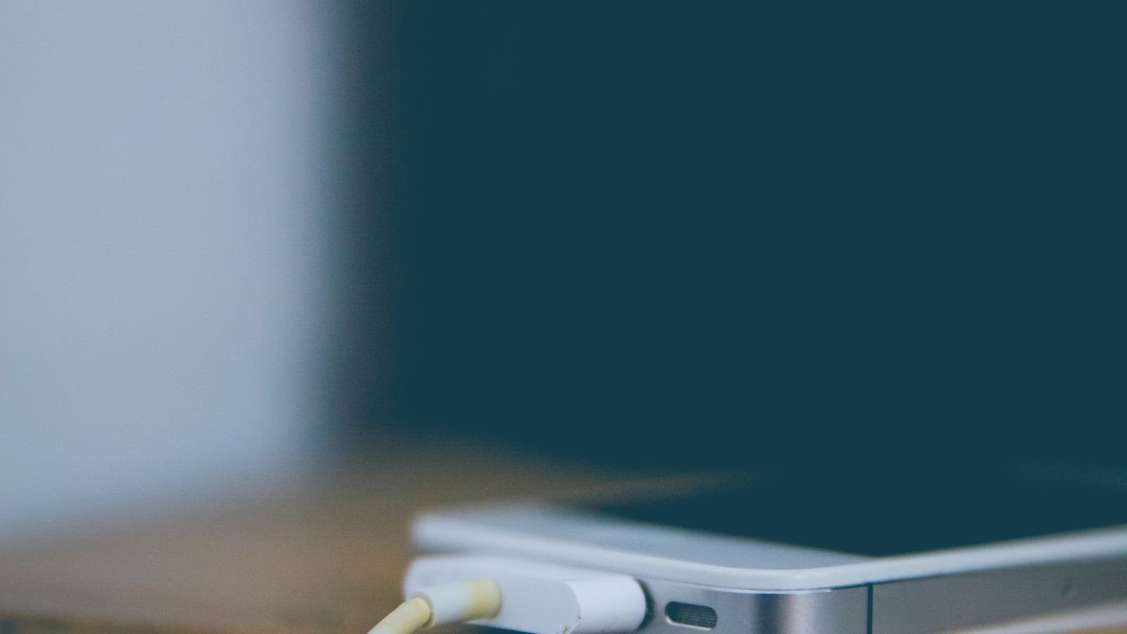 Smartphone charging on a wooden desk, close-up view