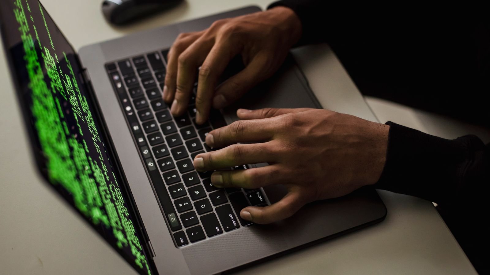 Close-up of hands typing on a laptop keyboard with a security themed screen