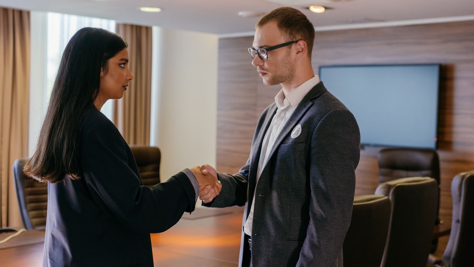 Two professionals shaking hands in a modern conference room