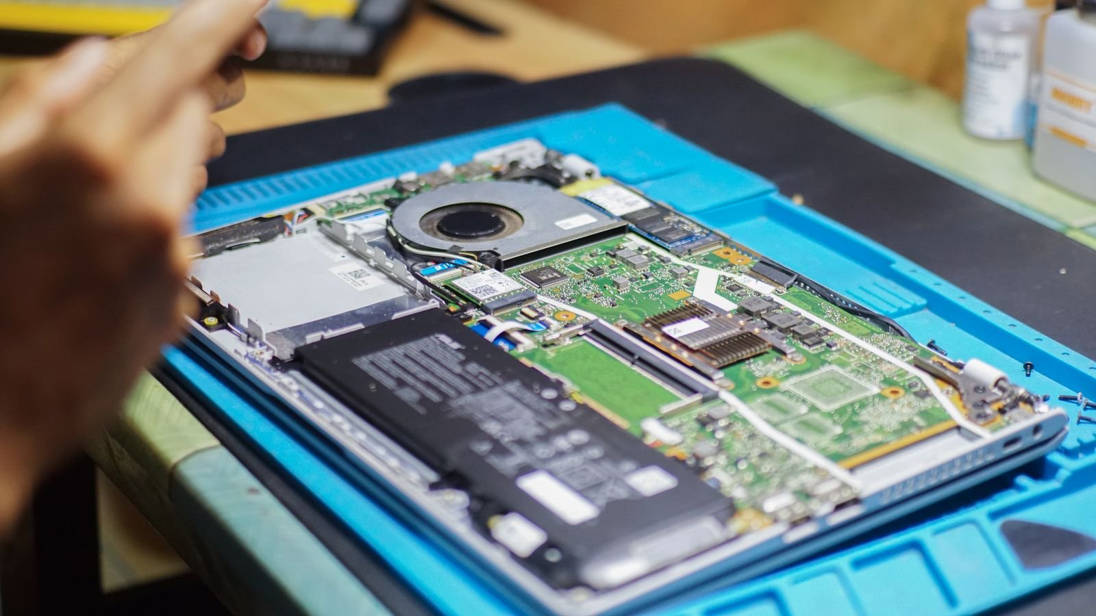 Close-up of a laptop being repaired with internal components and tools visible